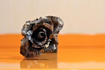 forged copper rose on orange background