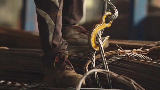Factory worker packing the metal aluminum profiles with strapping tape in manufacturing process at industrial metalwork plant. Product protection for transportation. Technology and industrial concept.