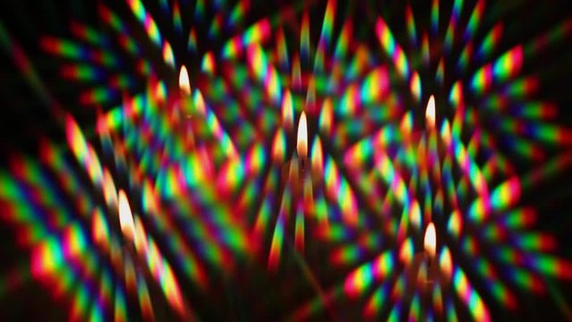 Rotating color highlights surrounding the flame of a candle as a halo. Diffraction of light from a candle flame as a set of diffraction orders, obtained using two rotating diffraction gratings
