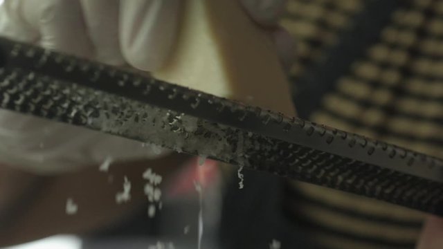Slow motion close up of hand in glove grating parmesan cheese from low angle.