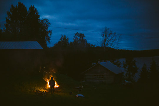 Silhouette of person looking at log fire