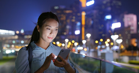 Woman look at cellphone at night in city