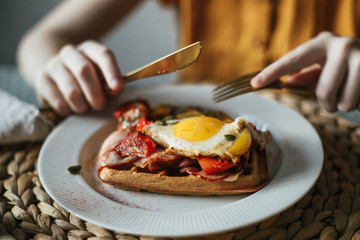 On a plate one Belgian waffle with egg and bacon