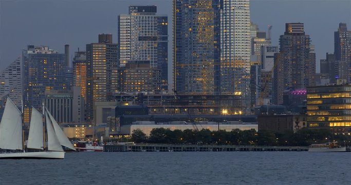 Panoramic dusk view of a sailing schooner on the Hudson River with Hudson Yards skyline in New York City.