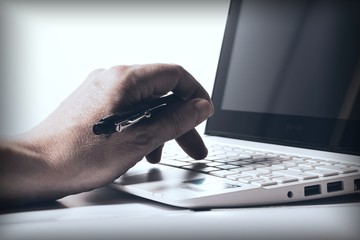 Background with the hand of a businessman working on a laptop keyboard. Back light. Business concept