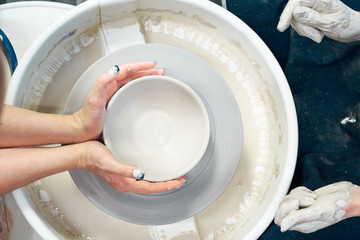 Woman making ceramic pottery, four hands close-up, focus on potters, palms with pottery, concept...