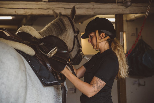 Woman preparing horse for ride