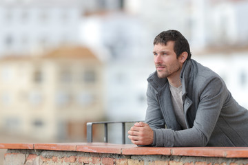 Serious man in winter looking away in a balcony