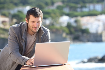 Serious man using a laptop in a balcony in winter