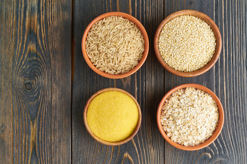 Set of groats for gluten-free fodmap diet, long carbohydrates, brown rice, corn, quinoa, oats. Mix of four sereals with lectine. Top view, close up, dark blue brown wooden background. Copy space