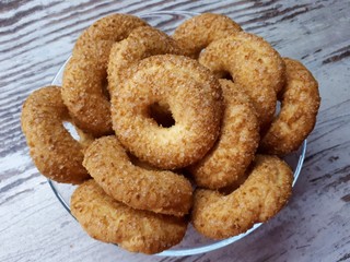  Close-up of cookies, tasty, homemade, fresh, shortbread, sprinkled with sugar, in a glass plate on a background of abstract wooden surface
