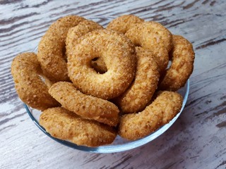  Close-up of cookies, tasty, homemade, fresh, shortbread, sprinkled with sugar, in a glass plate on a background of abstract wooden surface