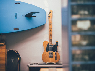 Blue surfboard hanging above electric guitar
