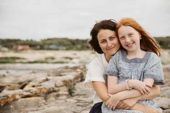 Mother and daughter embracing at seaside