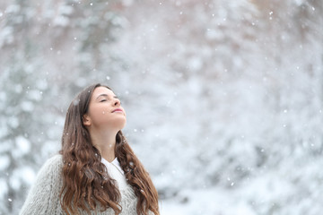 Relaxed girl breathing fresh air enjoying snow in winter