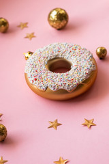 Christmas toys in the form of donut on a pink background with gold decor, selective focus, side view. Creative food minimalism