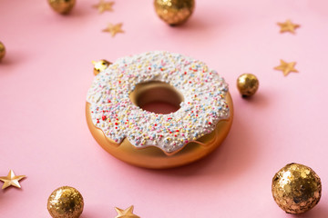 Christmas toys in the form of donut on a pink background with gold decor, selective focus, side view. Creative food minimalism