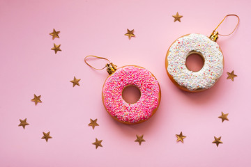Christmas toys in the form of donuts on a pink background with gold decor. Creative food...