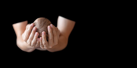Fototapeta premium Father holding head of his newborn baby in hands on black background. Loving father hands holding cute sleeping newborn baby child. Close up picture with copy space
