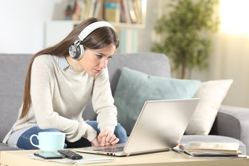 Serious girl e-learning with laptop and headphones