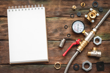 Plumbing flat lay background with copy space. Work tools, pipeline equipment and blank page notepad on plumber workbench. Fix list mockup.