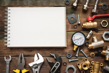Plumbing flat lay background with copy space. Work tools, pipeline equipment and blank page notepad on plumber workbench. Fix list mockup.