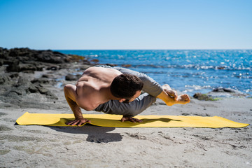 Muscular, Fit Man Doing Yoga Stretches Outside on a Beach In Morning Sunlight.