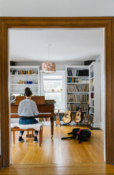 Stylish Teen Girl Playing Piano at Home with Dog next to her