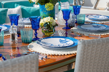 Beautiful table setting with a sea theme with blue wine glass cups and plates