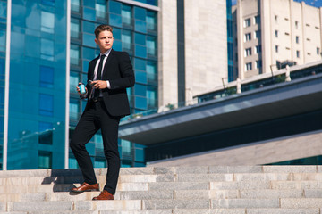 Young businessman drinks coffee in the street waiting for a meeting