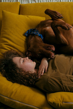 large portrait of a girl lying on a sofa and a dog playing