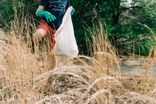 close up of little boy picking up trash for earth day