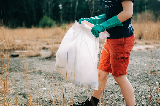 close up of little boy picking up trash for earth day