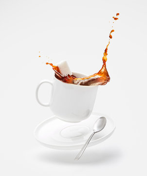 Falling cup with splashing coffee and sugar