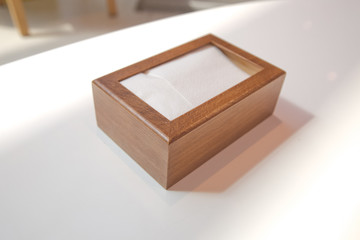 Wooden napkin holder with paper serviettes . Wooden brown empty napkin box . wooden stand with salt shaker, napkins on a wooden table in a cafe .