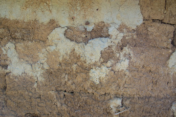 Old cracked wall made from mud and hay, exterior background, grunge texture with cracks for designs