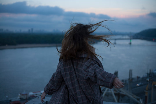portrait of a running girl with long hair against the backdrop of the river and the night city wind blows