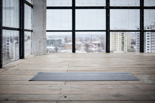 Empty Space In Fitness Center, Big Windows, Natural Wooden Floor, Modern Loft Studio, Unrolled Yoga Mat On The Floor. No People.