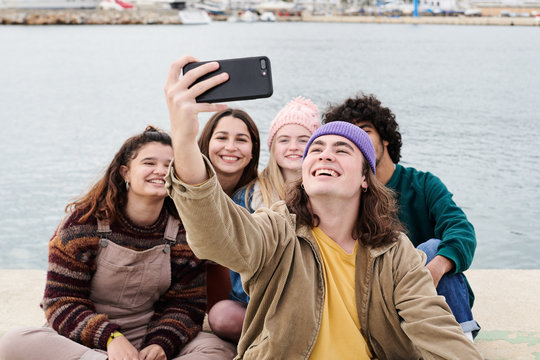 Cheerful friends taking selfie on pier