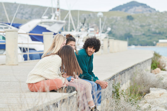 Relaxing teen friends sitting on coast