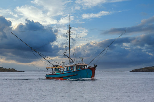 A blue shrimp boat trolling the grey waters of Alaska