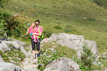 Naklejka na ściany i meble Mother and daughter hiking on a mountain path.