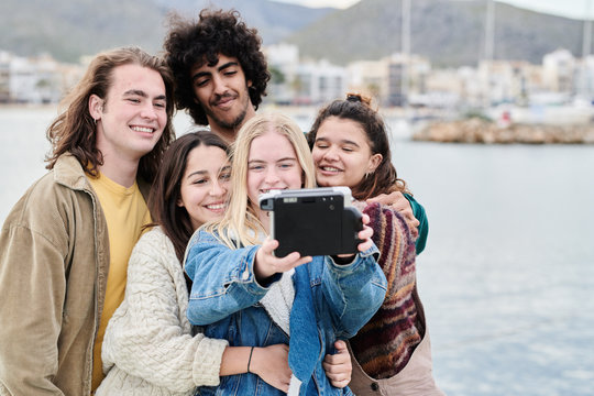 Teenage friends taking selfie with instant camera