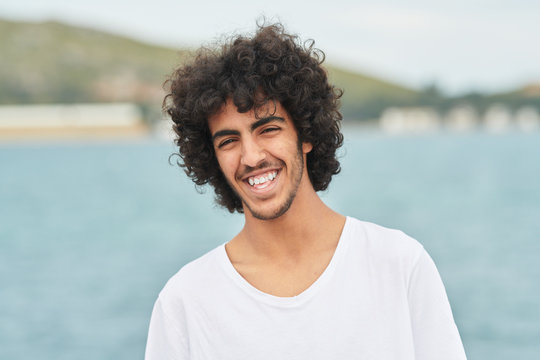 Teenager boy with curly hair spending time near lake.