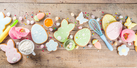 Easter cooking baking background with pastel colored easter cookies, sugar sprinkles and ingredients for bake cake and cookies.  Wooden rustic background, flatlay banner copy space