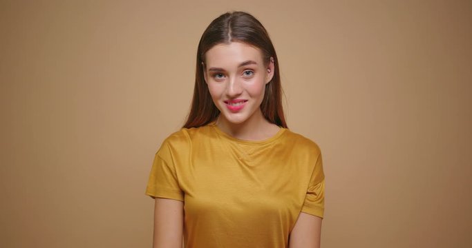 Funny woman in yellow t shirt make eyebrow dance isolated on beige background.