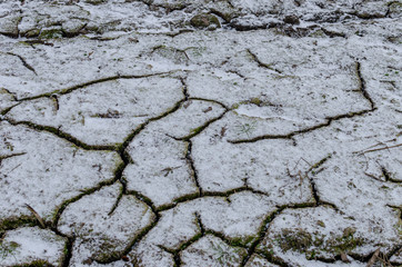 cracked earth texture in winter season with snow