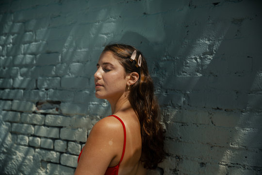 Young woman with barrettes in hair next to blue painted brick wall