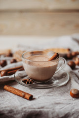 Hot cocoa with cookies, cinnamon sticks, anise, nuts on wooden background. Front view.