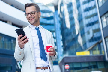 Business man using phone and holding cup of coffee